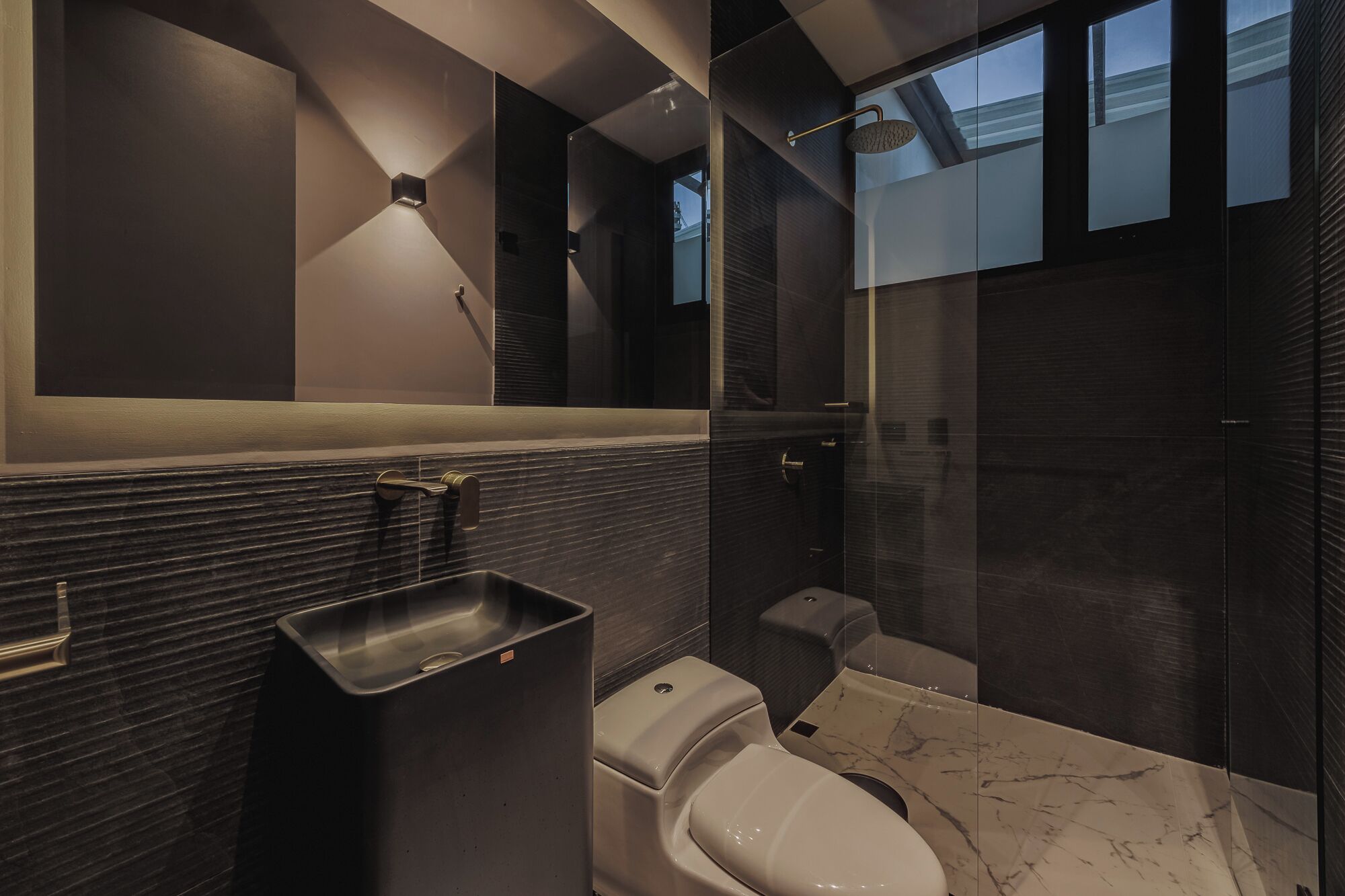 Une salle de bain moderne avec un lavabo en marbre, des toilettes et un espace douche.