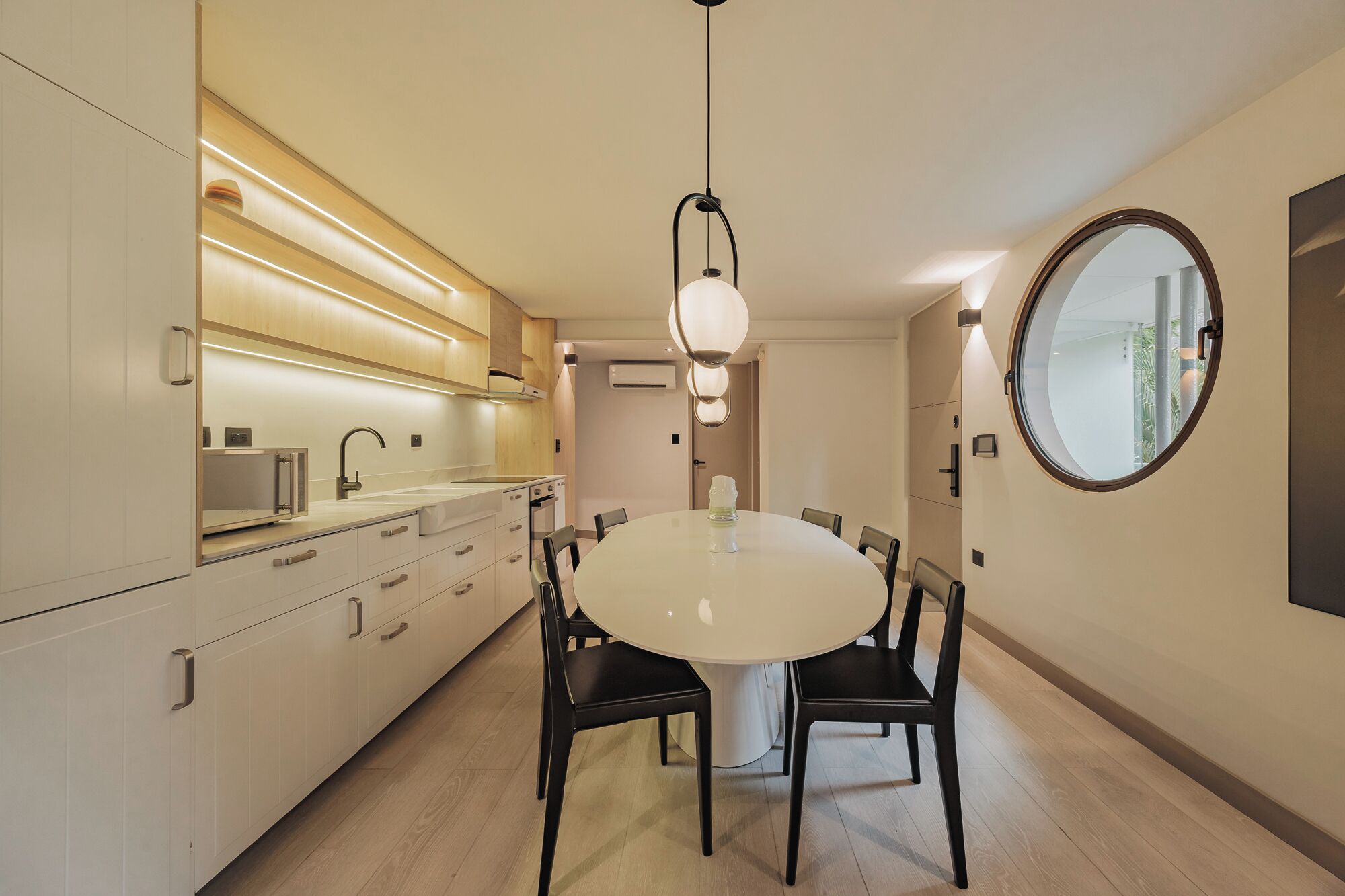 A modern kitchen with white cabinets, a round dining table, and black chairs.