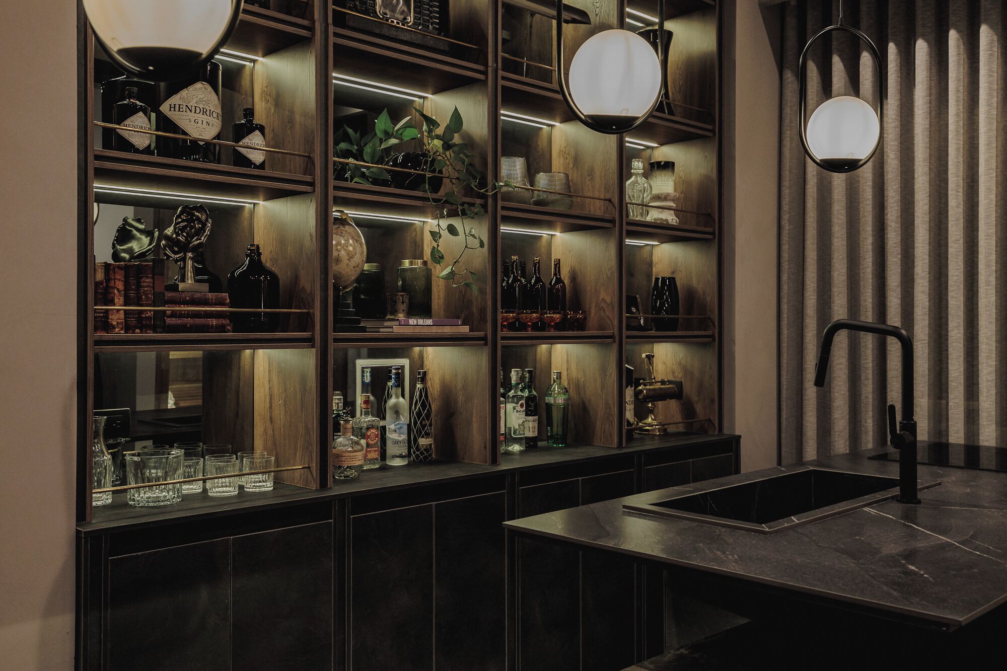 Angolo bar con scaffali pieni di bottiglie, bicchieri e oggetti decorativi.