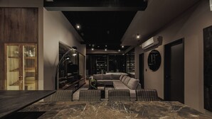 A modern living room with a marble floor, a sectional sofa, a large flat-screen TV, and a built-in bookshelf. - Revellion by EP (Medellín)