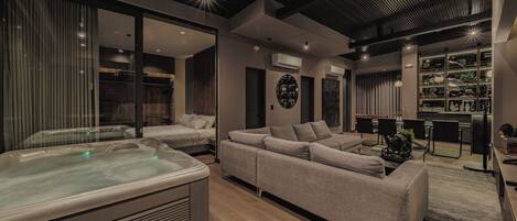 A modern living room with a large sofa, a hot tub, and a bar area.