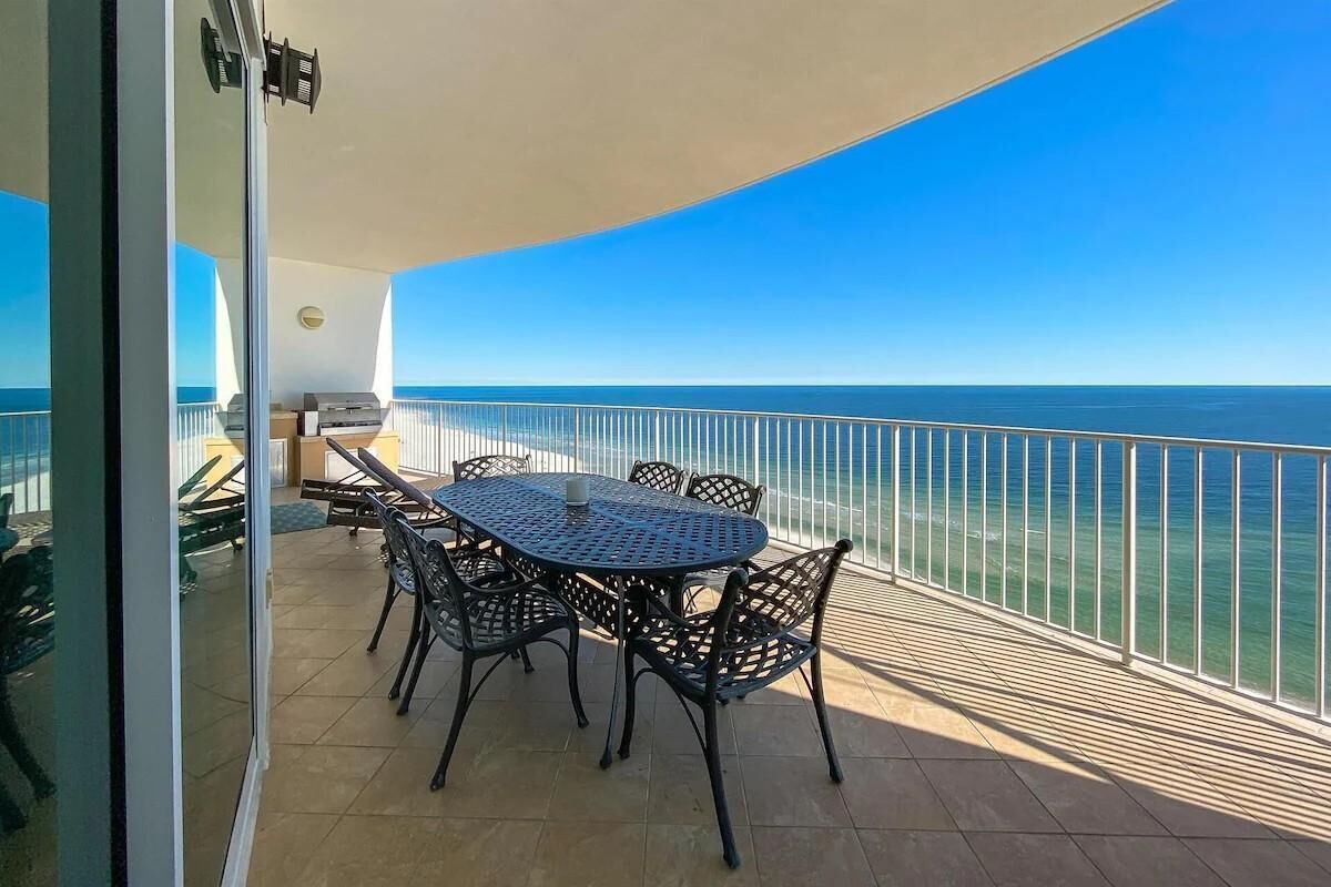 A balcony with a table and chairs, overlooking a clear blue sea.
