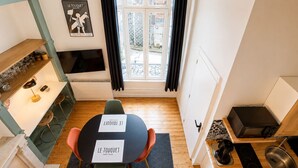 A compact kitchen with a dining area, a TV, and a window with curtains. - Comfortable studio in the heart of Le Touquet (Le Touquet-Paris-Plage)