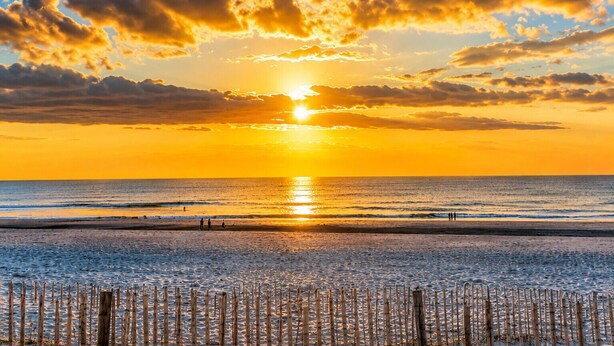 A beach with a sunset, waves, and a fence in the foreground. - Comfortable studio in the heart of Le Touquet (Le Touquet-Paris-Plage)
