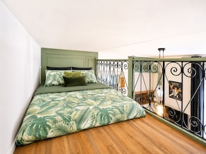 A bedroom with a bed, green headboard, and a balcony with a wrought iron railing. - Comfortable studio in the heart of Le Touquet (Le Touquet-Paris-Plage)