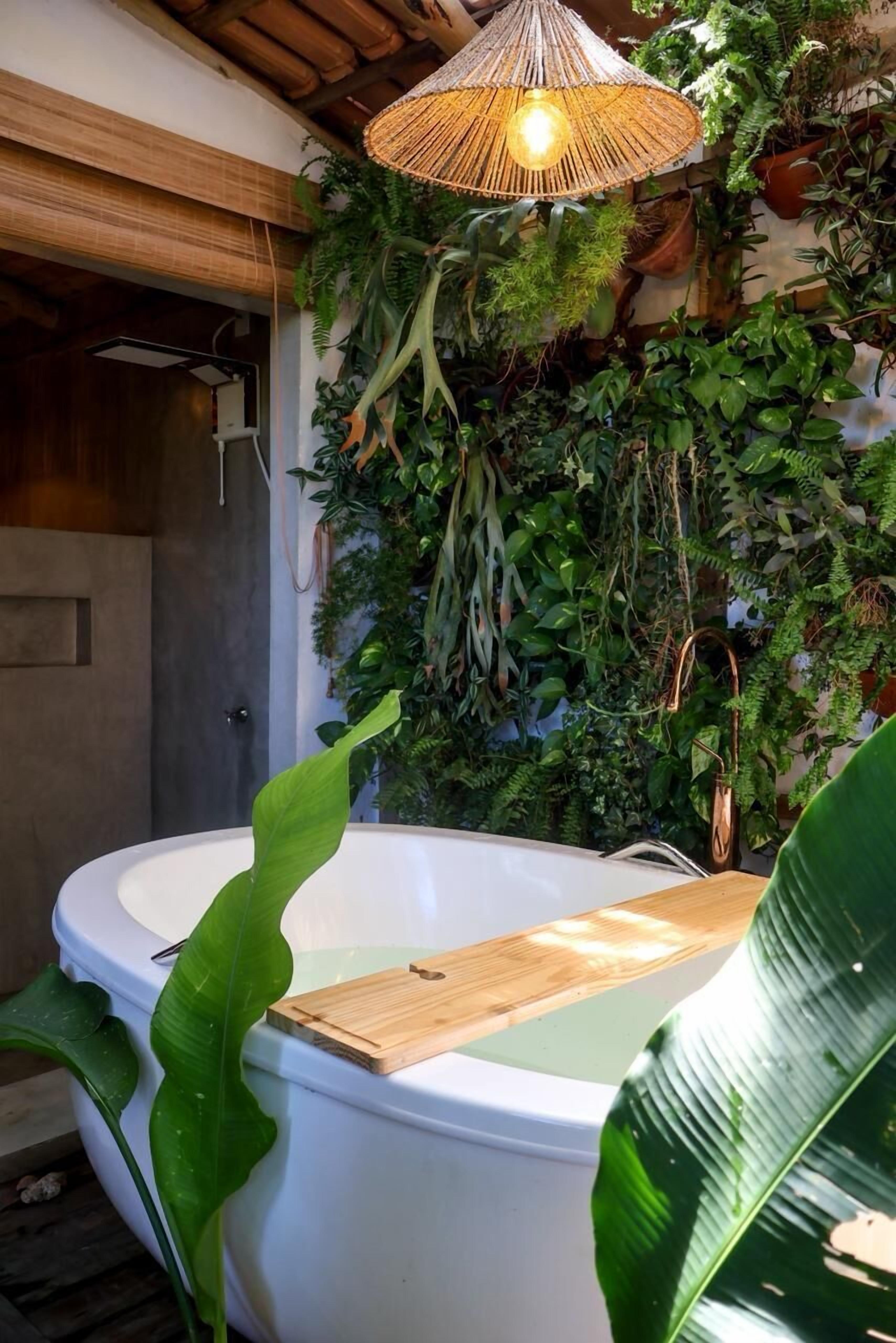 A bathroom with a white bathtub, a wooden cutting board, and a hanging light fixture.
