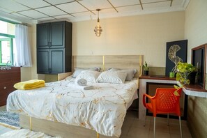 Un dormitorio con cama, escritorio, silla, armario e iluminación colgante.