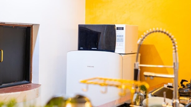 Una cocina con microondas, refrigerador blanco y un lavamanos con grifo.