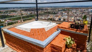 Una terraza en la azotea con hidromasaje, paredes de ladrillo y plantas en macetas.