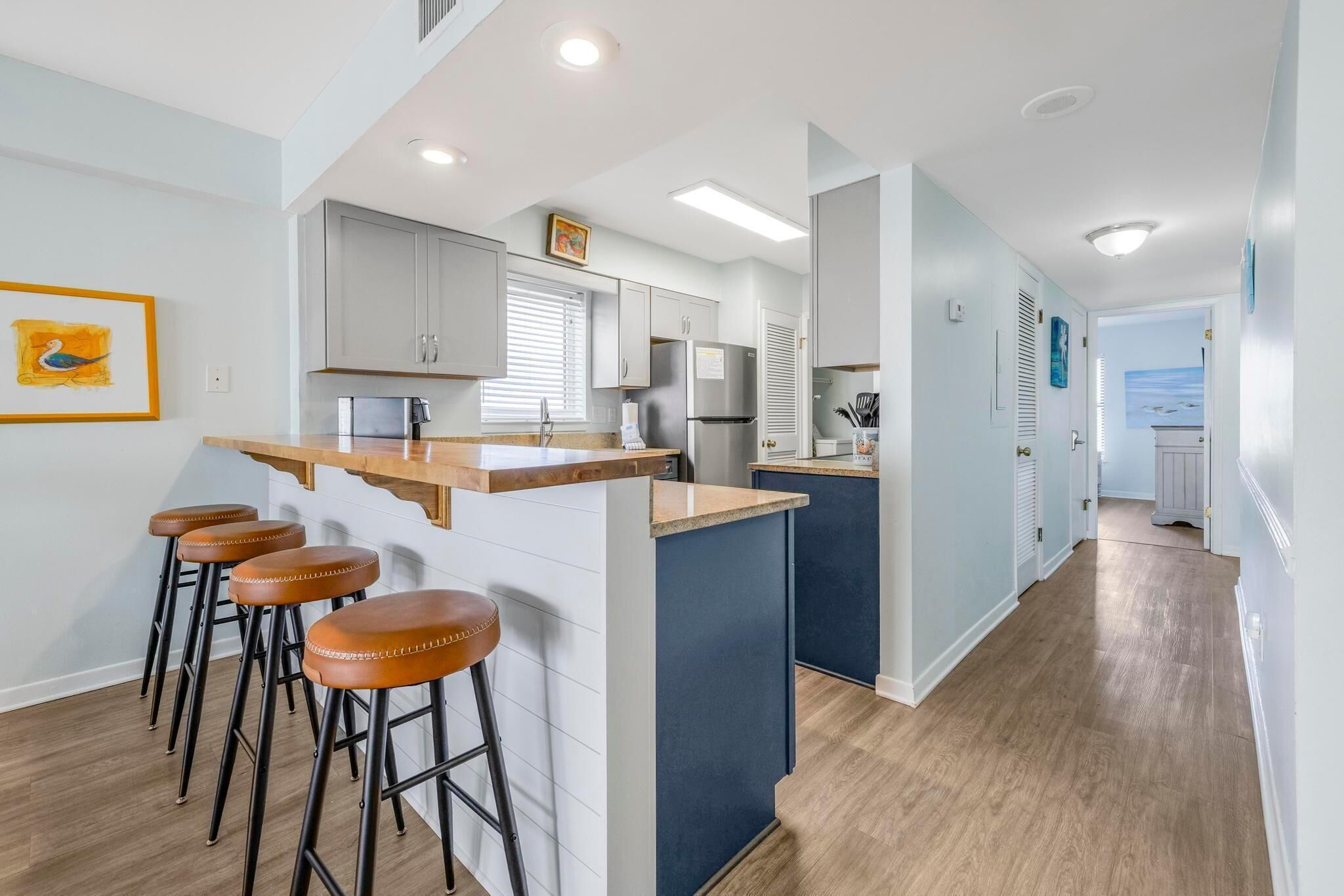 A modern kitchen with a central island, bar stools, and a view of the living area.