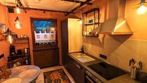 A compact kitchen with a built-in stove, a sink, and a window with a view of a snowy landscape. - Wohnen in der Galerie (Worpswede)