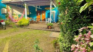 Ein kleines, farbenfrohes Haus mit einer Veranda, einer H ängematte und zahlreichen Blumentöpfen.