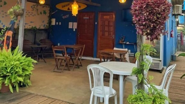 Eine Terrasse im Freien mit Tischen, Stühlen, hängenden Pflanzen und einer blauen Wand.