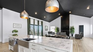 A modern kitchen with a large island, stainless steel appliances, and pendant lighting. - New! Sunset Acres ~ Ideal for all Occasions! (Clermont)