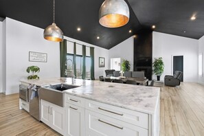Una cocina moderna con una isla grande, electrodomésticos de acero inoxidable e iluminación colgante.