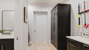 A modern kitchen with dark cabinets, a white countertop, and a wooden floor. - New! Sunset Acres ~ Ideal for all Occasions! (Clermont)