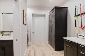 Una cocina moderna con armarios oscuros, encimera blanca y suelo de madera.