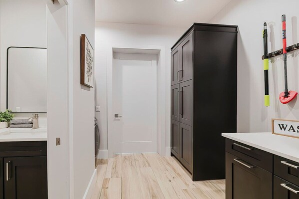 A modern kitchen with dark cabinets, a white countertop, and a wooden floor. - New! Sunset Acres ~ Ideal for all Occasions! (Clermont)