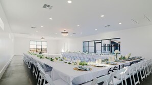 A spacious conference room with white tables and chairs, large windows, and a chandelier. - New! Sunset Acres ~ Ideal for all Occasions! (Clermont)