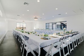 A spacious conference room with white tables and chairs, large windows, and a chandelier. - New! Sunset Acres ~ Ideal for all Occasions! (Clermont)