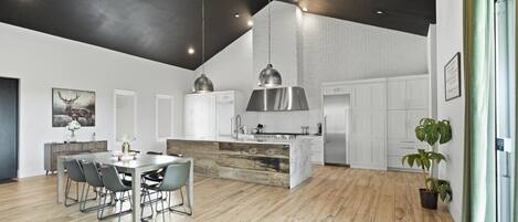 Una cocina moderna con armarios blancos, una isla central e iluminación colgante.