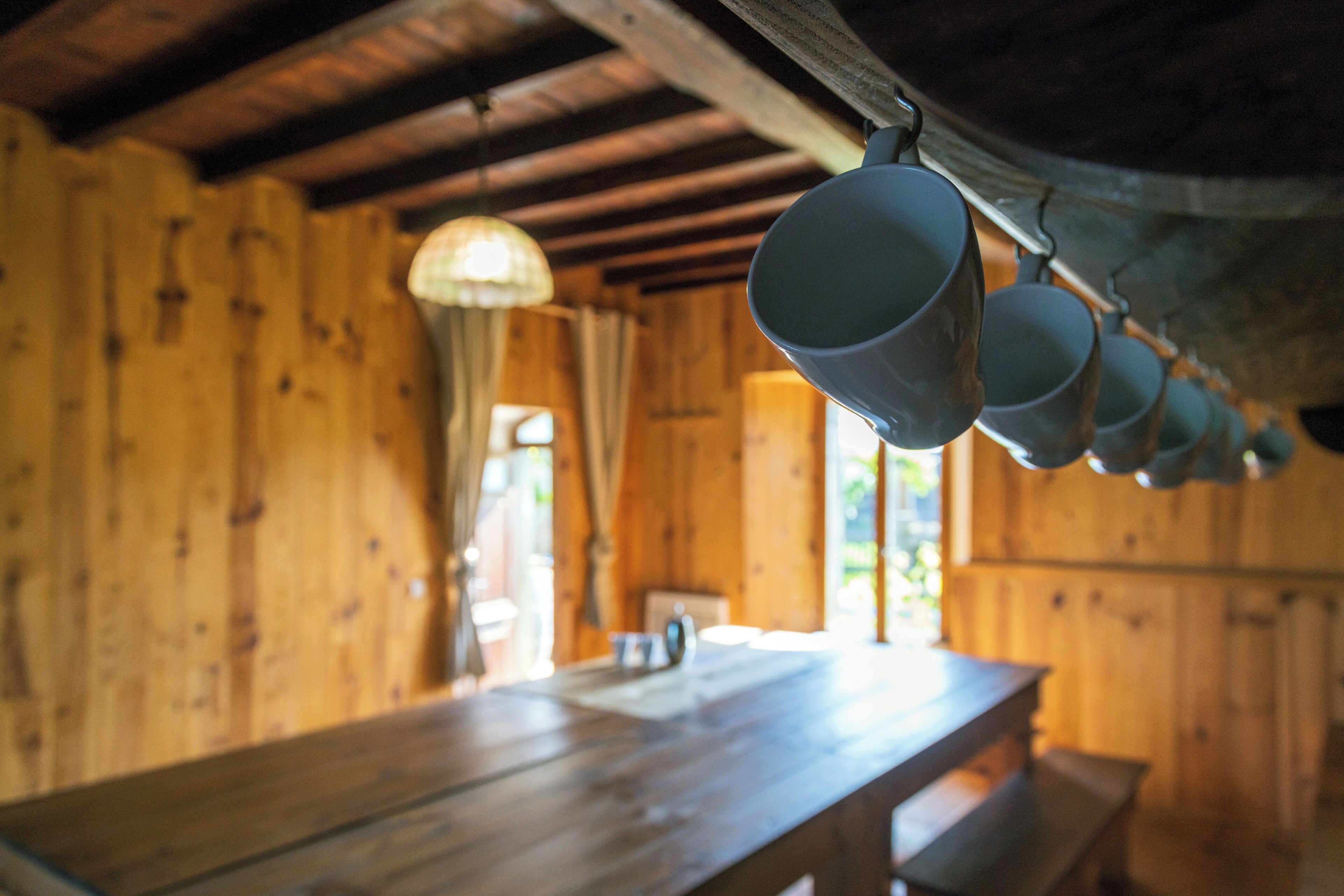 Un intérieur en bois avec une longue table et des tasses suspendues.