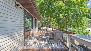 Une terrasse dotée de mobilier d’extérieur, d’une porte-fenêtre et offrant une vue sur un lac.