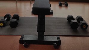 Une salle de sport équipée d’un banc, d’haltères et d’une chaise.