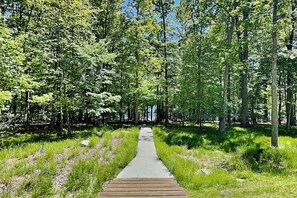 A wooden pathway leading through a forested area with trees and grass. - Wisp Water Lodge (McHenry)