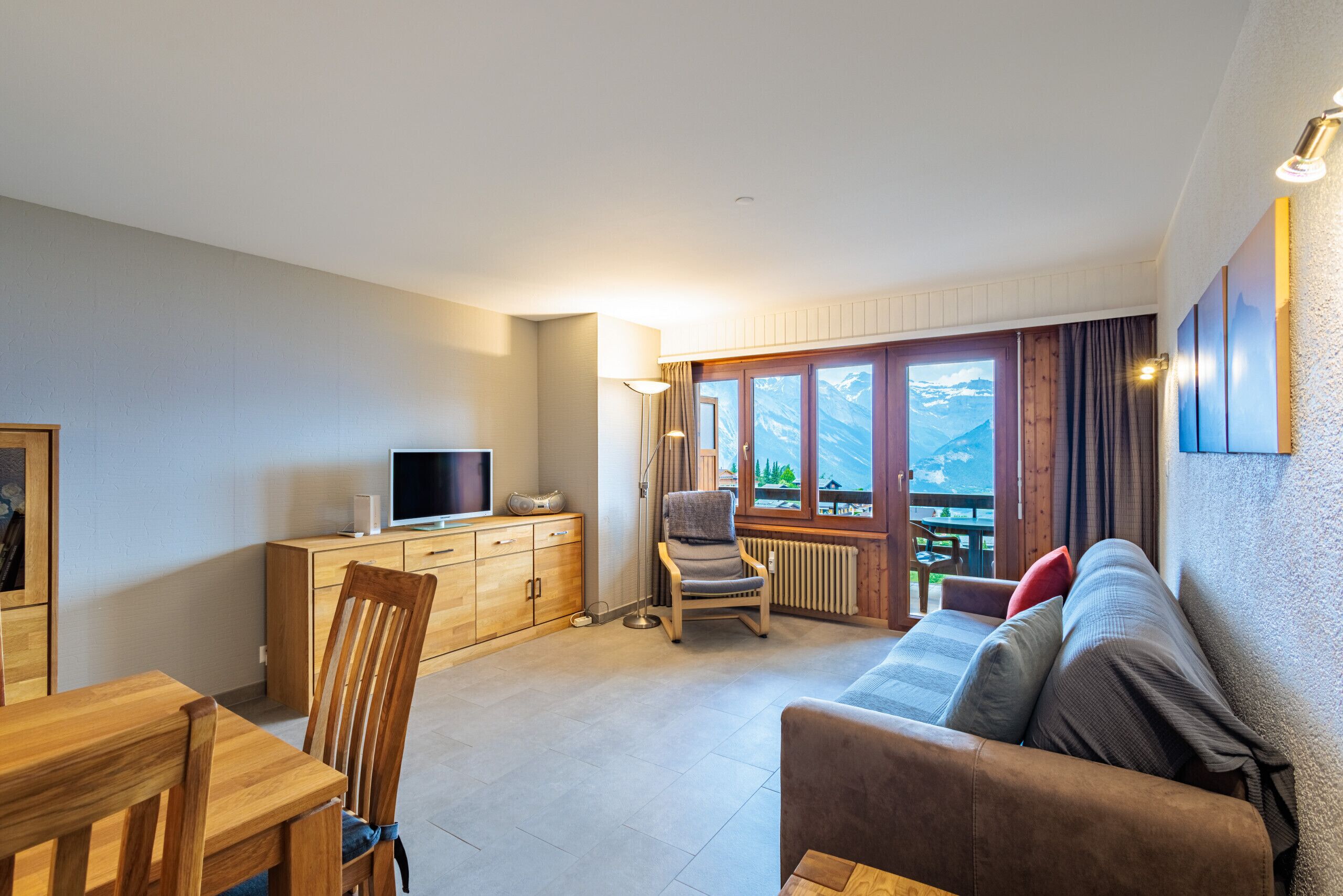 Ein gemütliches Wohnzimmer mit einem Holzesstisch, einer Couch und einem Fernseher auf einer Holzkommode.