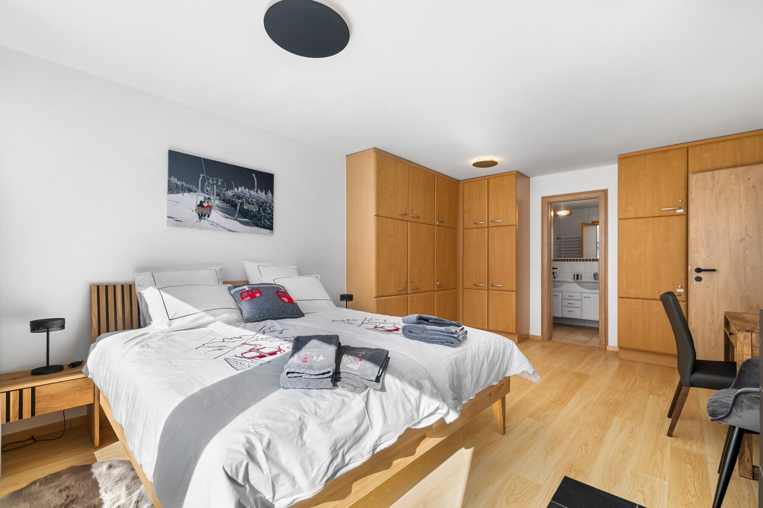A bedroom with a bed, bedside table, and a painting on the wall.