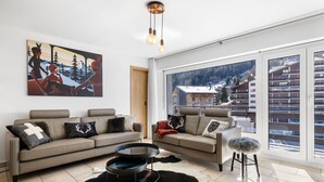 A modern living room with a large window, a sofa, a coffee table, and a painting on the wall. - Christiania I A8 - 6 pers - ski in&out (Haute-Nendaz)
