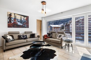 A modern living room with a large window, a sofa, a coffee table, and a painting on the wall. - Christiania I A8 - 6 pers - ski in&out (Haute-Nendaz)