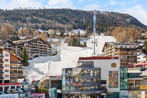 En skidort med flera byggnader, inklusive ett hotell med balkonger och en skidlift i bakgrunden.