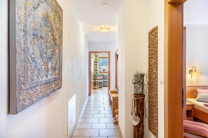 A hallway with a patterned wall, a wooden door, and a bed with a striped pillow. - Apartment 'Landhaus Zeller 2 Schlafzimmer' with Mountain View, Shared Garden and Wi-Fi (Fügenberg)