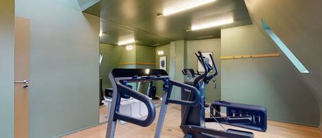 A gym with treadmills, exercise bikes, and a mirrored wall.