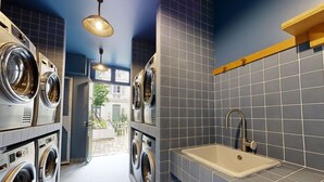 A laundry room with multiple washing machines, a sink, and a view of the outside. - Joivy Delightful 1-bed Studio w/ Shared Co-working (Paris)