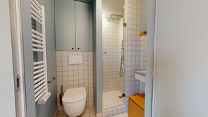 A compact bathroom with a toilet, a shower, and a small sink. - Joivy 10 Douai 1BR Velux (Paris)