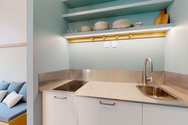 A modern kitchen with a built-in stove, a sink, and a shelf above the countertop. - Joivy Delightful 1bed Studio w/ Shared Co-working (Paris)