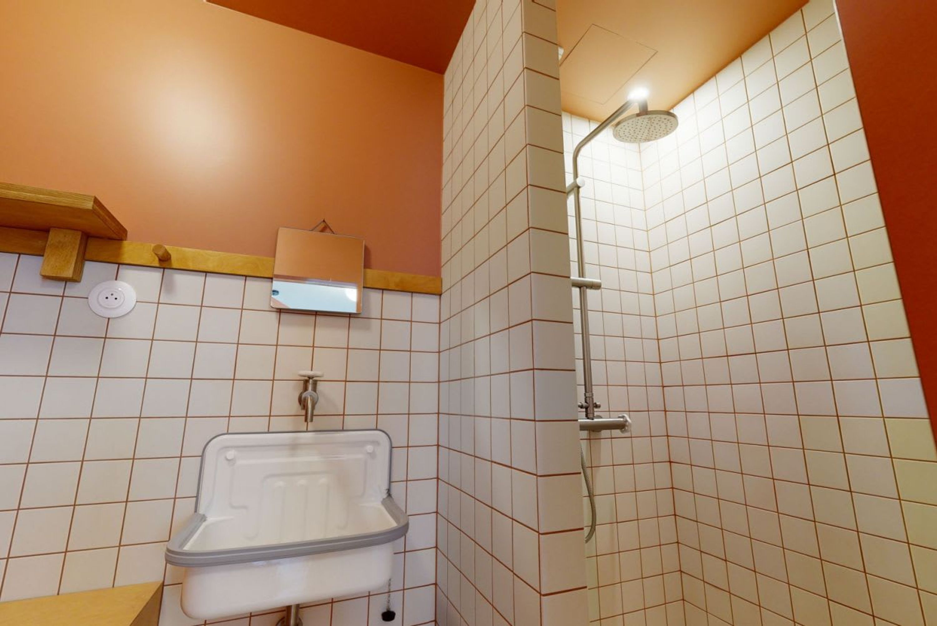 A bathroom with a sink, a shower, and tiled walls.