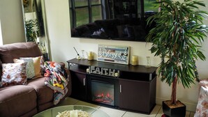 A living room with a brown sofa, a glass coffee table, a fireplace, a television, and a potted plant. - Home located  10 minute from Hard Rock Stadium Home of the FIFA World Cup 2026  (Miramar)