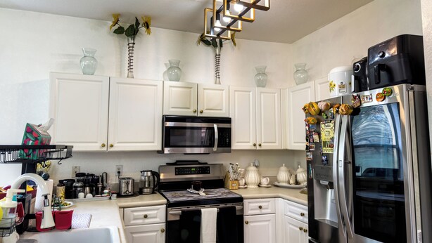 A modern kitchen with white cabinets, stainless steel appliances, and decorative items. - Home located  10 minute from Hard Rock Stadium Home of the FIFA World Cup 2026  (Miramar)