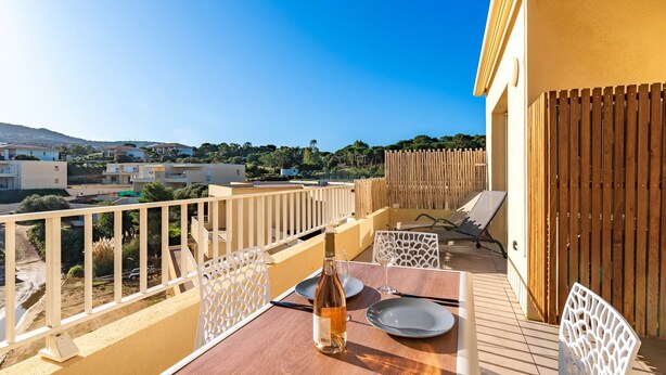 Ein Balkon mit Tisch für zwei Personen, einer Weinflasche und Blick auf die Umgebung.