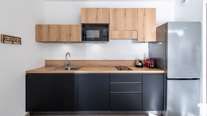 Eine moderne Küche mit schwarzen Schränken, einer Holzarbeitsplatte, einem Edelstahlkühlschrank und einer Mikrowelle.