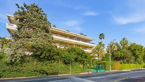 A multi-story building with balconies, surrounded by lush greenery and palm trees. - La Rose des Vents - Cannes (Cannes)