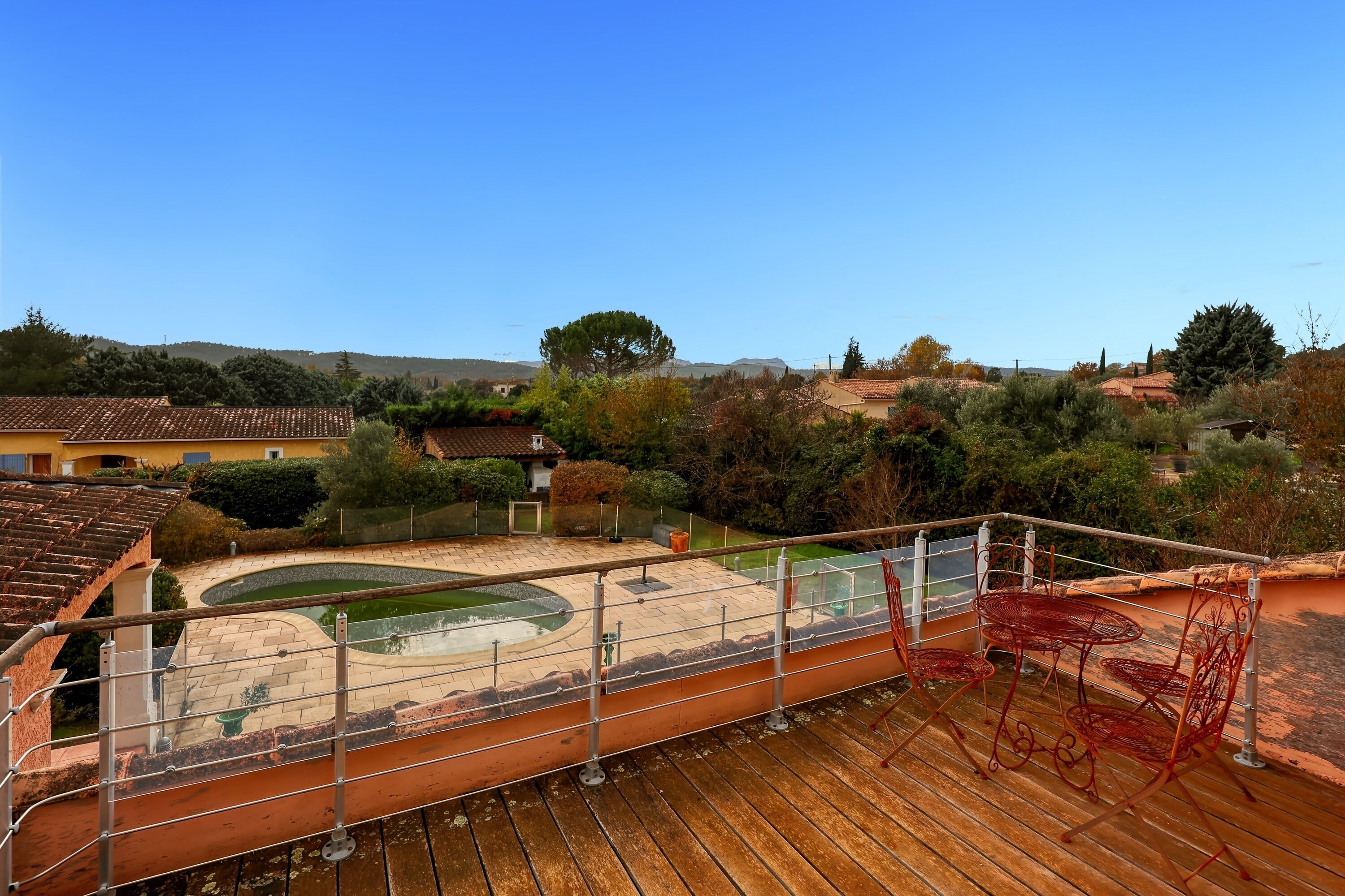 Eine Dachterrasse mit Pool, Gartenmöbeln und Blick auf die umliegende Landschaft.