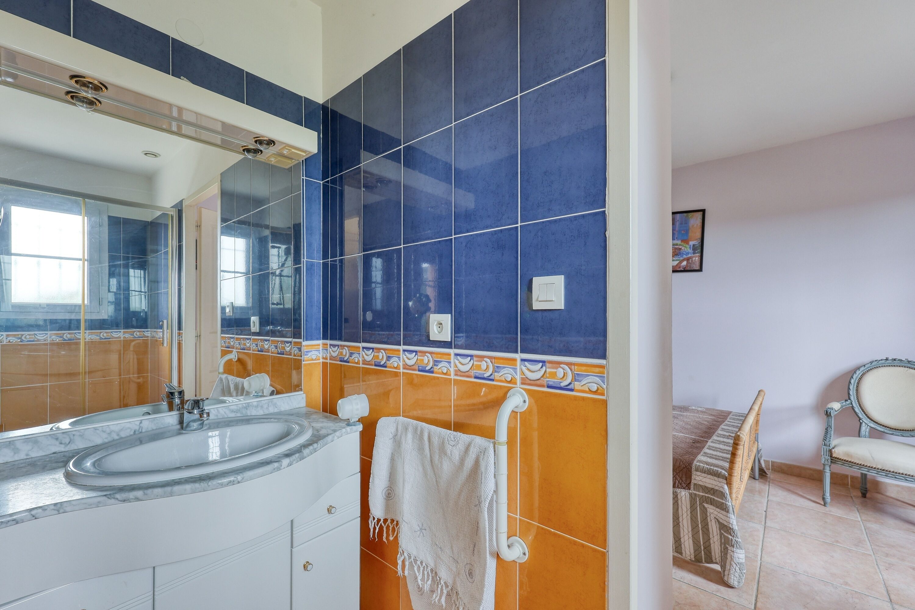 Een badkamer met een grote spiegel, twee wasbakken en een handdoekrek.
