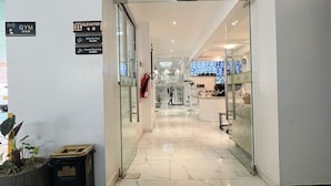 A hotel entrance with a reception desk, a gym sign, and an elevator sign. - Pazoori Stays at SmartHomes Yaya Centre (Nairobi)
