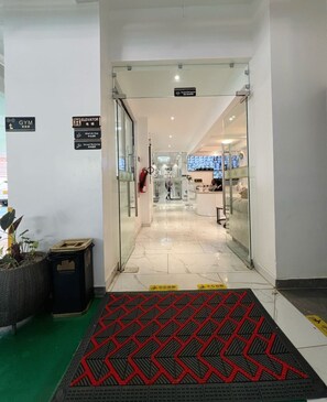 A hotel entrance with a reception desk, a gym sign, and an elevator sign. - Pazoori Stays at SmartHomes Yaya Centre (Nairobi)