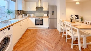 Una cocina moderna con armarios blancos, horno empotrado, microondas y refrigerador.